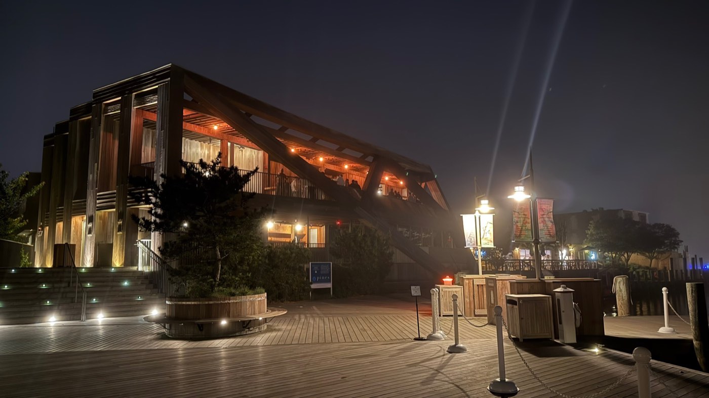The Pavilion in Fire Island Pines lit up at night over the harbor boardwalk.